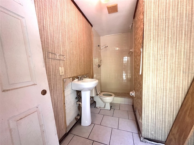 bathroom featuring tile patterned flooring, a tile shower, and toilet