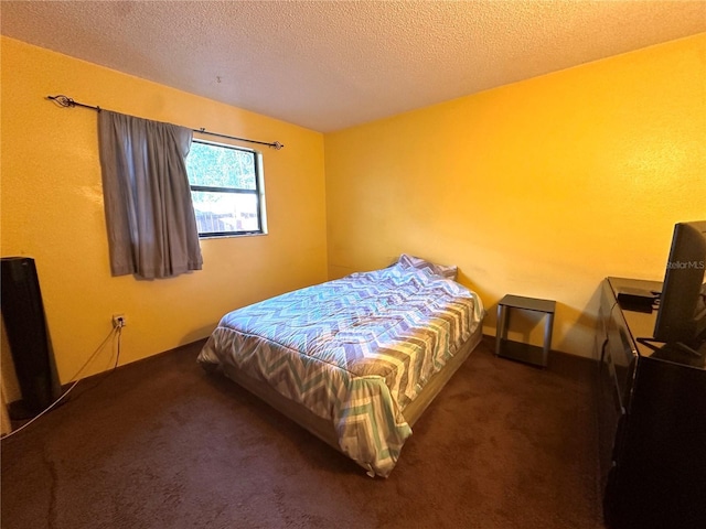 bedroom with a textured ceiling and dark colored carpet