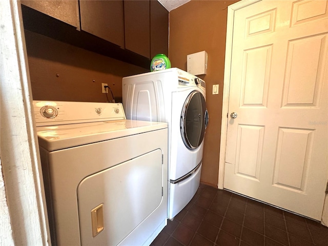 laundry area featuring dark tile patterned floors, cabinets, and washer and clothes dryer