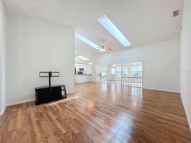 unfurnished living room featuring hardwood / wood-style flooring, ceiling fan, and lofted ceiling with skylight