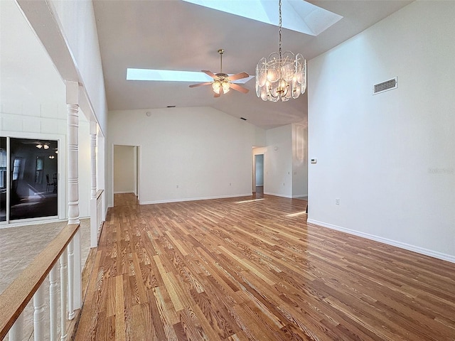 unfurnished living room featuring a skylight, high vaulted ceiling, ceiling fan with notable chandelier, and hardwood / wood-style flooring