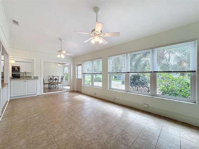 interior space featuring ceiling fan, sink, light tile patterned flooring, and vaulted ceiling