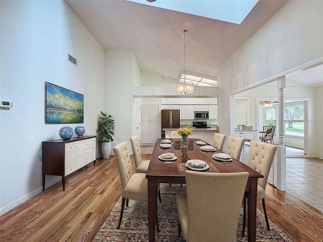 dining room featuring high vaulted ceiling, wood-type flooring, and ceiling fan with notable chandelier