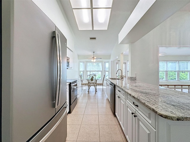 kitchen featuring stainless steel appliances, ceiling fan, sink, light tile patterned floors, and white cabinets