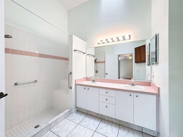 bathroom with ceiling fan, tiled shower, and vanity