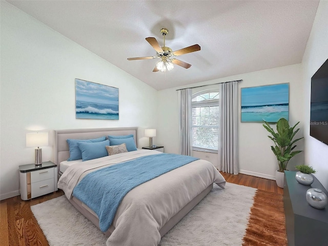 bedroom featuring wood-type flooring, a textured ceiling, vaulted ceiling, and ceiling fan