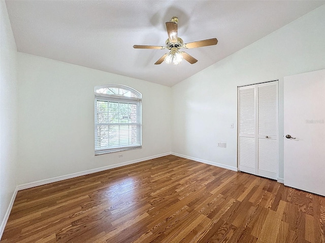 unfurnished bedroom with lofted ceiling, ceiling fan, a closet, and dark hardwood / wood-style floors