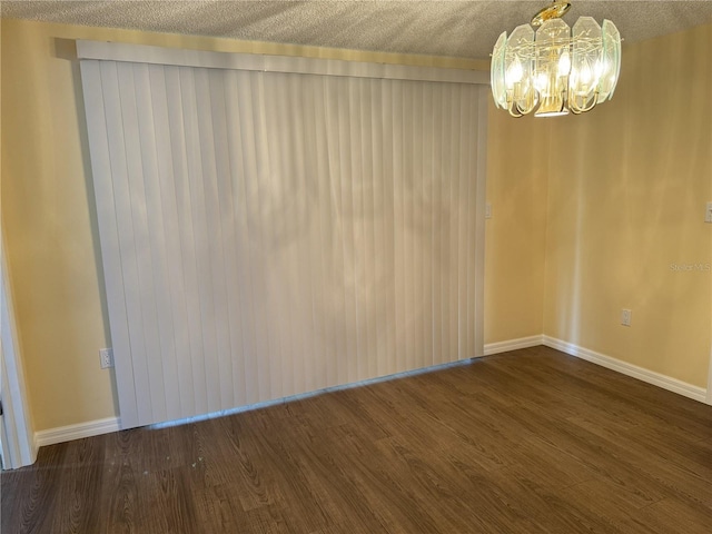 unfurnished room with dark hardwood / wood-style flooring, a textured ceiling, and an inviting chandelier