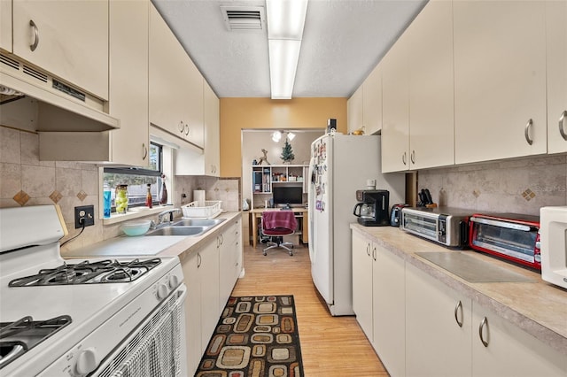 kitchen featuring sink, white appliances, light hardwood / wood-style floors, and decorative backsplash