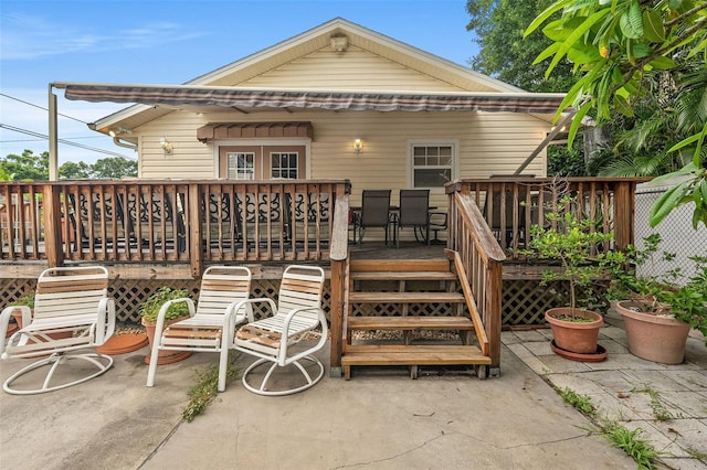 rear view of property with a wooden deck and a patio