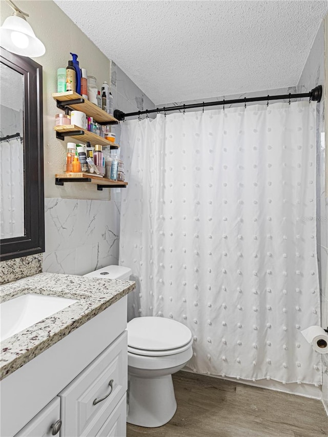 bathroom with toilet, a textured ceiling, vanity, wood finished floors, and a shower with curtain