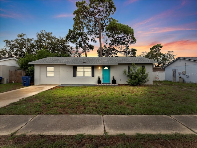 ranch-style home featuring a lawn, fence, and stucco siding