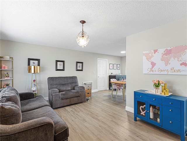 living room with hardwood / wood-style flooring, a notable chandelier, and a textured ceiling