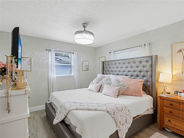 bedroom with a textured ceiling and light hardwood / wood-style floors