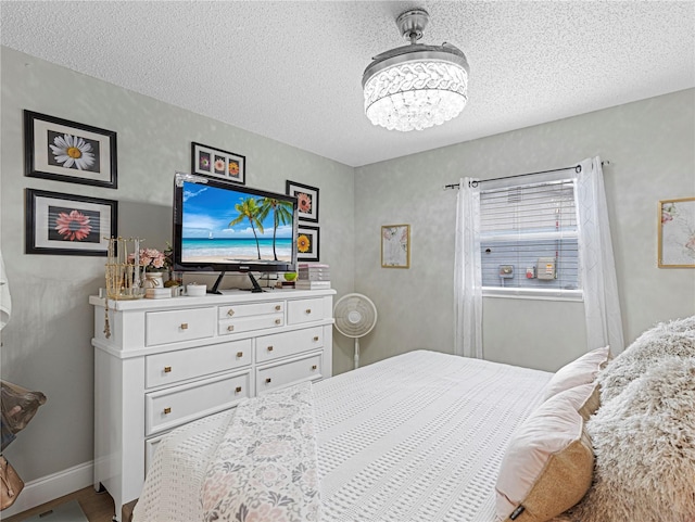 bedroom with baseboards, a chandelier, and a textured ceiling