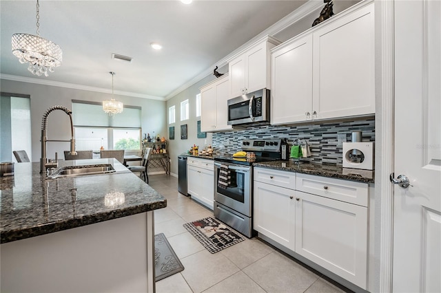 kitchen featuring white cabinetry, decorative light fixtures, sink, dark stone countertops, and appliances with stainless steel finishes