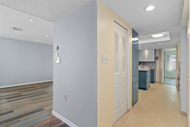 hallway with a textured ceiling and light tile patterned floors