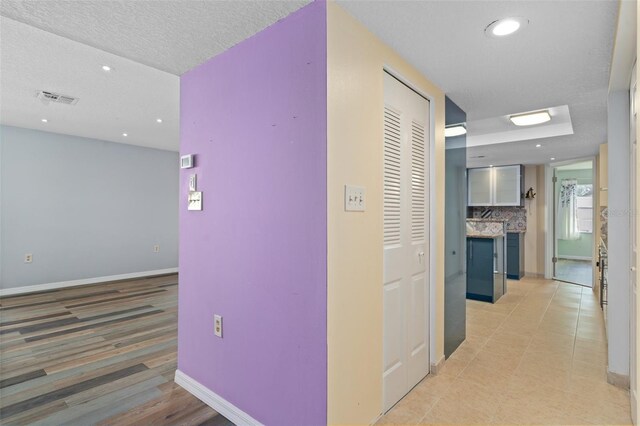 hall with light hardwood / wood-style floors and a textured ceiling