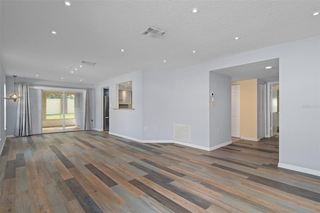 unfurnished living room featuring hardwood / wood-style flooring and a textured ceiling