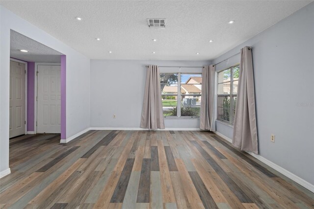 empty room featuring wood-type flooring and a textured ceiling