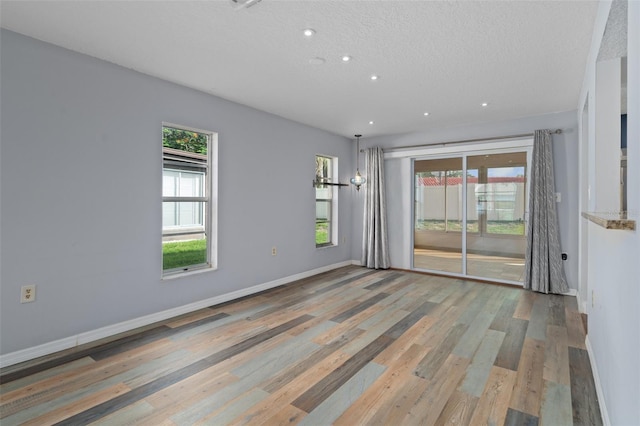 empty room with wood-type flooring and a textured ceiling