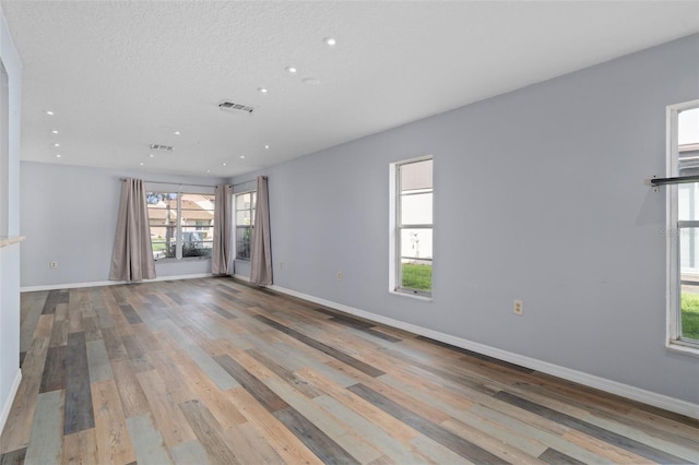 unfurnished living room featuring a textured ceiling and hardwood / wood-style floors