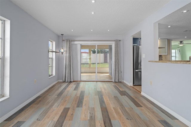 empty room with a textured ceiling, ceiling fan, and wood-type flooring