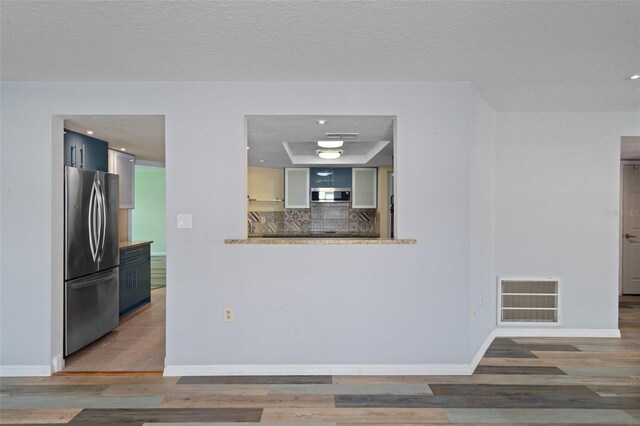 kitchen with decorative backsplash, stainless steel appliances, hardwood / wood-style floors, and a textured ceiling