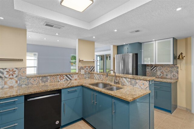 kitchen featuring stainless steel appliances, sink, kitchen peninsula, light stone counters, and decorative backsplash