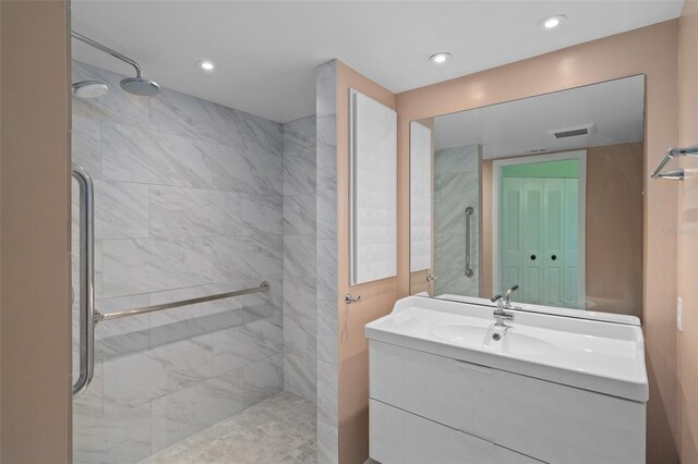 bathroom featuring tiled shower and vanity