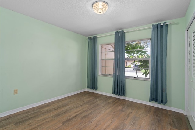 spare room with a textured ceiling and dark hardwood / wood-style flooring