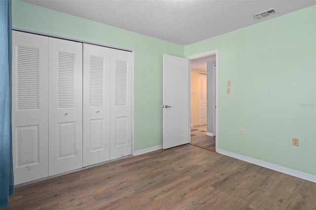 unfurnished bedroom featuring a textured ceiling, hardwood / wood-style flooring, and a closet