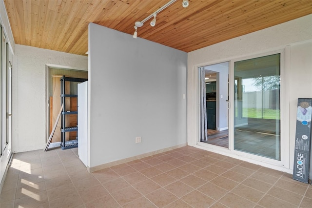 empty room with rail lighting, tile patterned flooring, and wooden ceiling