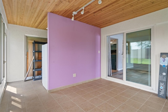 empty room featuring wooden ceiling, tile patterned flooring, and track lighting