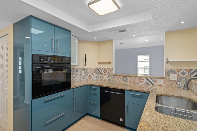 kitchen featuring light tile patterned floors, a tray ceiling, black appliances, blue cabinetry, and decorative backsplash