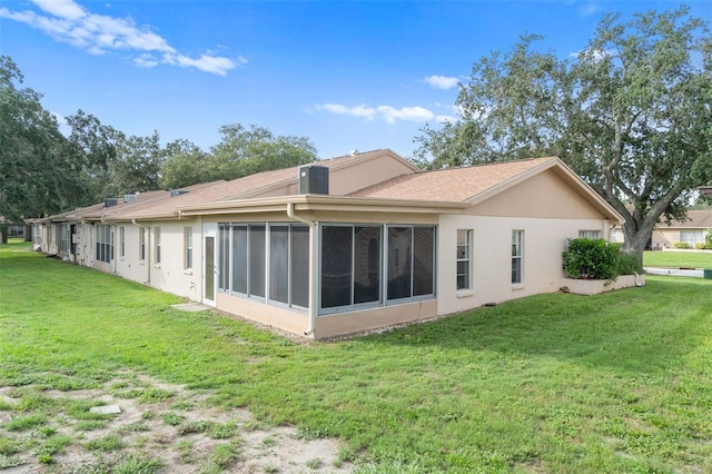 back of property featuring a sunroom and a lawn