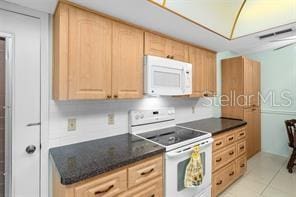 kitchen featuring light tile patterned flooring, light brown cabinetry, and white appliances