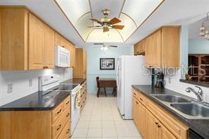 kitchen with ceiling fan, sink, light tile patterned floors, and white appliances