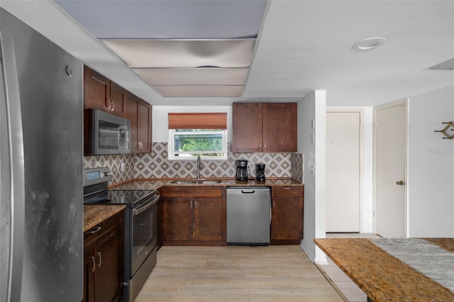 kitchen with stainless steel appliances, sink, light wood-type flooring, and decorative backsplash