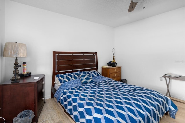 bedroom with ceiling fan, light hardwood / wood-style floors, and a textured ceiling