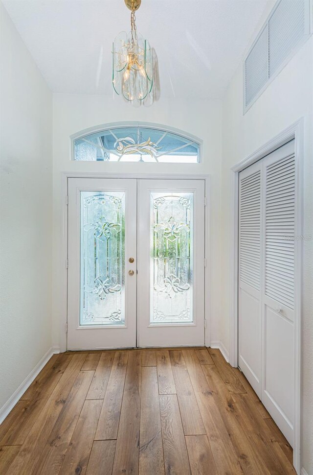 entrance foyer featuring french doors, light hardwood / wood-style flooring, and a notable chandelier