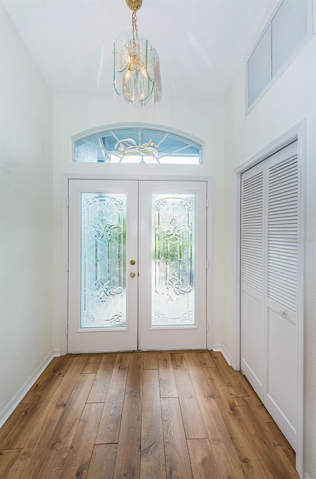 entryway featuring french doors, an inviting chandelier, and light hardwood / wood-style flooring