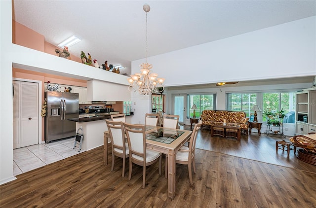 dining space featuring high vaulted ceiling, light hardwood / wood-style floors, a chandelier, and a wealth of natural light