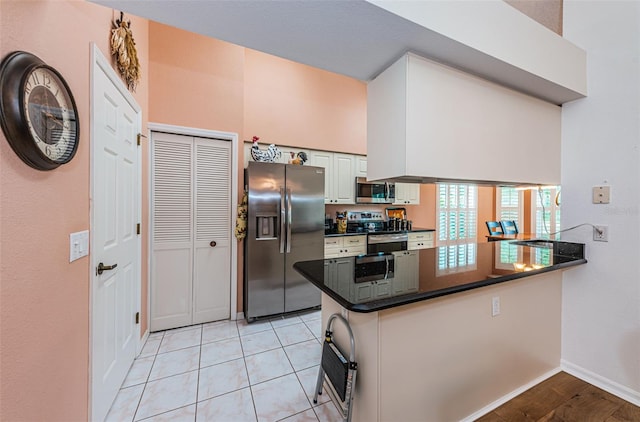 kitchen with white cabinetry, stainless steel appliances, light tile patterned floors, and kitchen peninsula