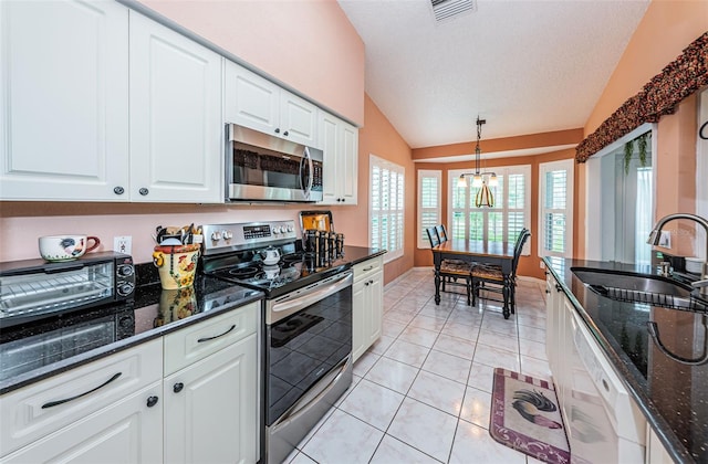 kitchen with stainless steel appliances, vaulted ceiling, pendant lighting, sink, and white cabinetry