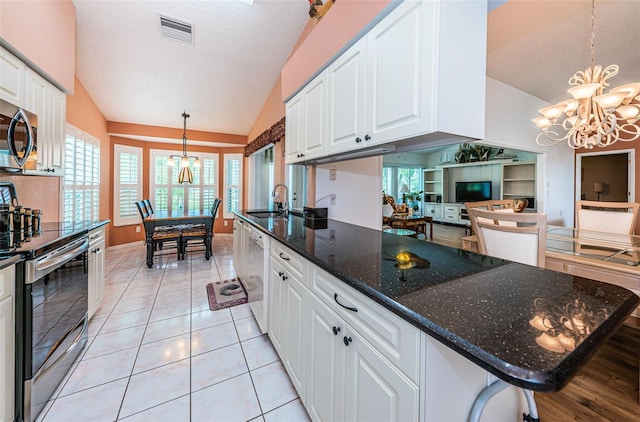 kitchen featuring white cabinets, stainless steel appliances, a notable chandelier, and decorative light fixtures