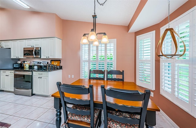 dining room with a notable chandelier, plenty of natural light, light tile patterned flooring, and vaulted ceiling