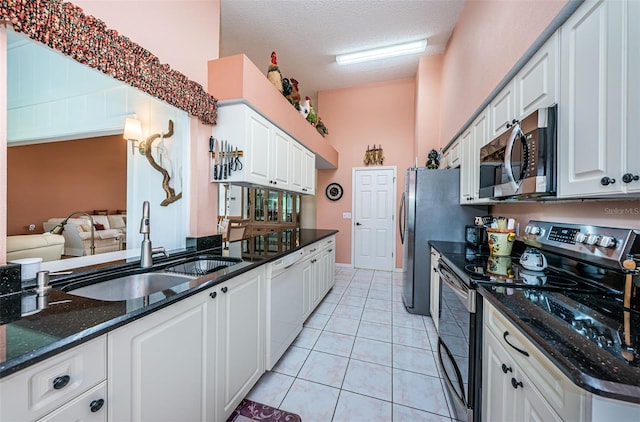 kitchen featuring white cabinetry, dark stone counters, stainless steel appliances, sink, and a textured ceiling