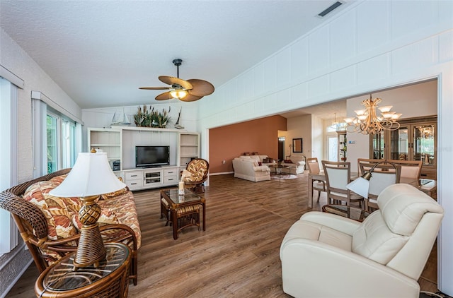 living room featuring vaulted ceiling, ceiling fan with notable chandelier, and hardwood / wood-style floors