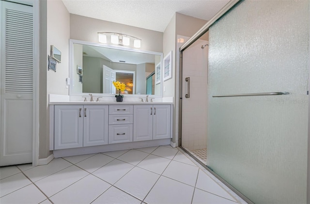 bathroom featuring a textured ceiling, tile patterned flooring, vanity, and a shower with door